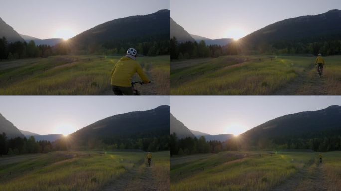 日出时，成熟的男性骑自行车进入草地
