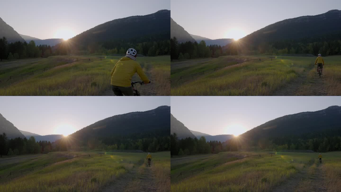 日出时，成熟的男性骑自行车进入草地