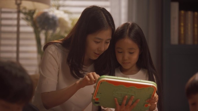 一位年轻的韩国母亲带着可爱的小女儿在锻炼，两人都在用平板电脑玩学习游戏。焦点转移到父子玩积木