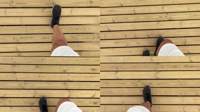穿着短裤和运动鞋的男子走在木地板上。主观镜头。走路。木头。一步一步来。锻炼
