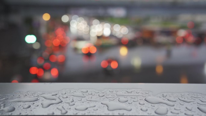 雨落在高架人行道的金属扶手上，背景是交通堵塞