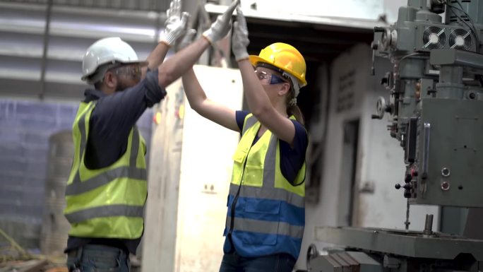 两组不同的阿拉伯工程师男性和高加索技术工人女性在制造工厂修理机器。开心的击掌跳，兴奋的跳舞，工作结束