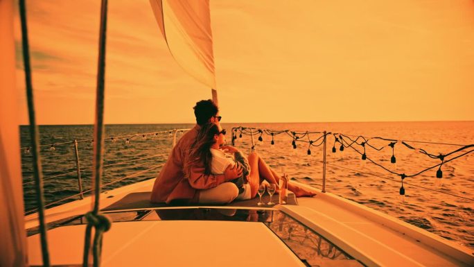 度假时坐在帆船甲板上的年轻夫妇