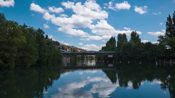 利马特河在瑞士苏黎世的欧洲大桥下流动。低角度看，阳光明媚的夏日，桥上来往的车辆，浮云飘过，河上漂浮着