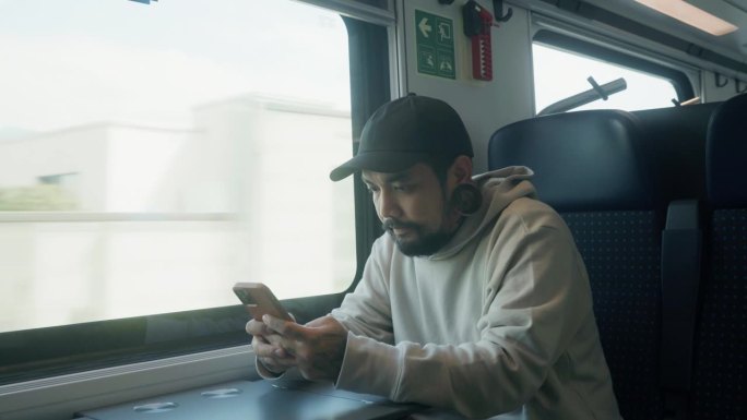 自信的亚洲通勤男子乘火车旅行，在商务代表团期间用手机工作和发短信，检查电子邮件。