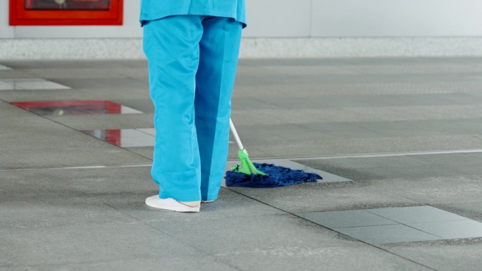 特写长柄拖把，这是滥用清洁人员用拖把弄脏地板，因为这是公共区域，整天有很多人走过，使地方看起来一直干