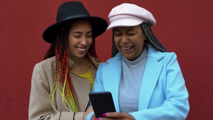 快乐的非洲母亲和女儿在冬天的城市里一起玩手机