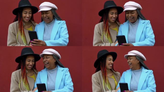 快乐的非洲母亲和女儿在冬天的城市里一起玩手机