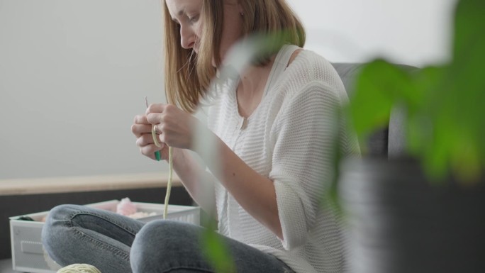 一位女士编织优雅的amigurumi，将纱线编织成均匀的环，创造出令人难忘的纺织玩具，将成为孩子们的