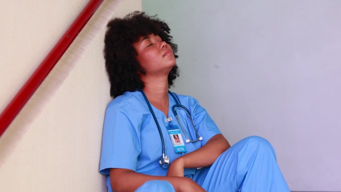 疲惫不堪的实习护士或女医生坐在医院的楼梯上。医疗保健和医药概念