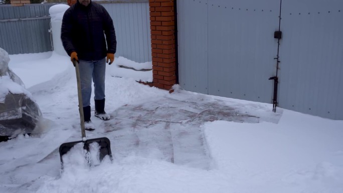 一个男人用铁铲铲雪。