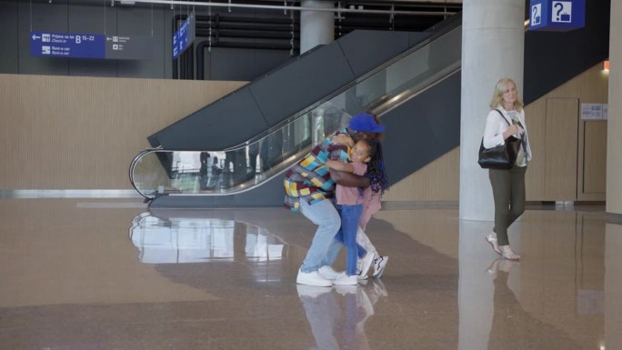 一名非洲男子在机场的入境区迎接家人时很高兴