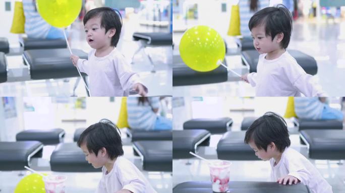 快乐的亚洲男孩在商场吃冰淇淋玩气球。