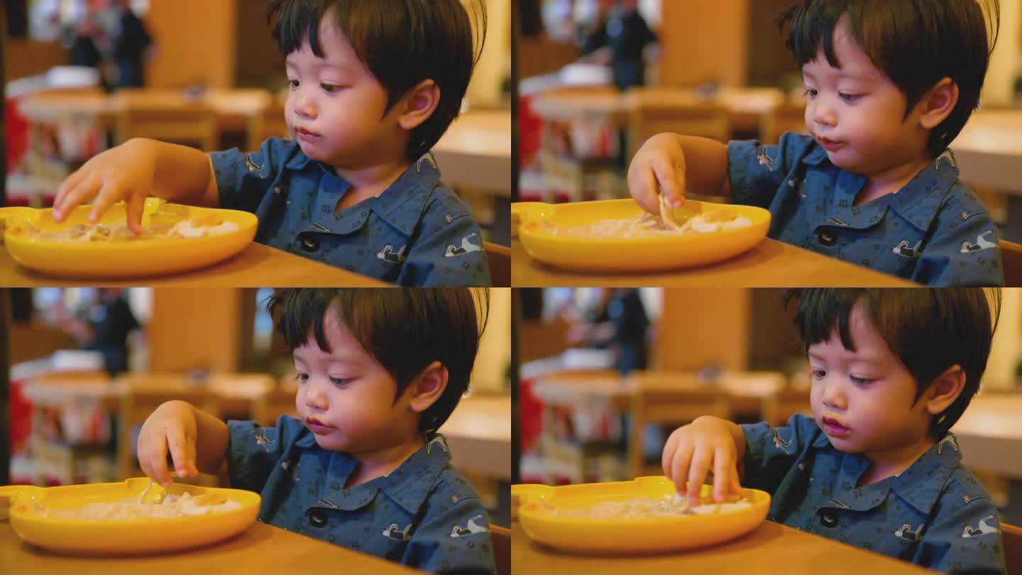 快乐的亚洲男孩用手吃日本面条。美味的。