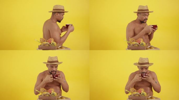 中年非洲裔美国人，有胡子，裸体，拿着一杯热巧克力，享受早晨无压力的宁静心情。一个黑人男子坐在黄色背景