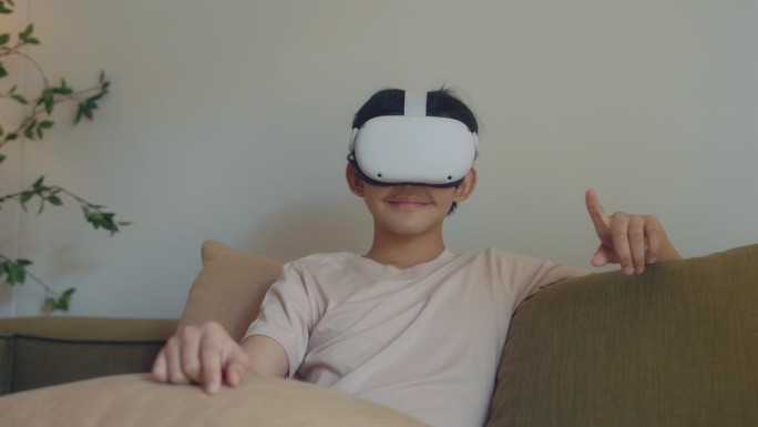 快乐的男孩坐在客厅的沙发上体验虚拟现实。