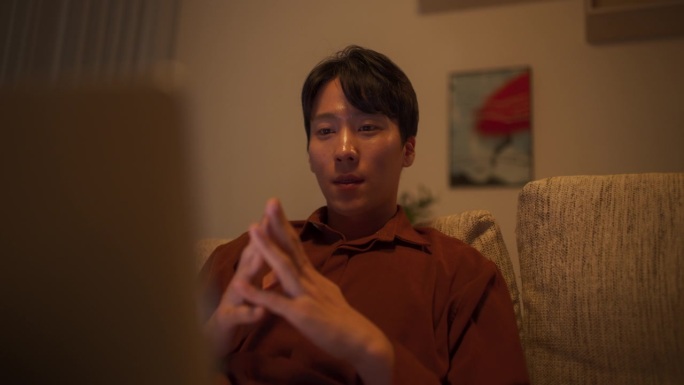一个韩国男性的肖像专注于虚拟工作从家里，使用笔记本电脑进行生产任务管理，为他的经理创建详细的报告和演
