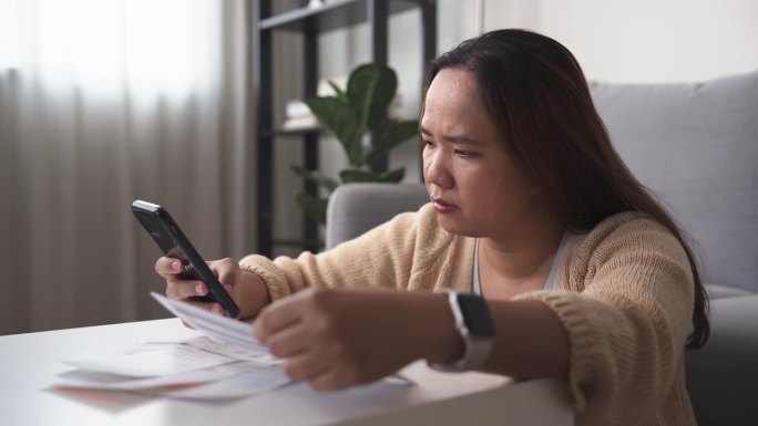 压力大的亚洲女性用智能手机管理自己的财务账单