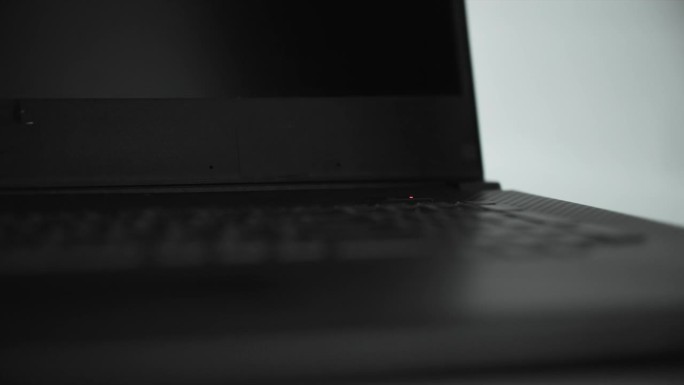 女人用手按下键盘上的电脑电源键，笔记本背光打开，特写