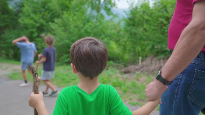 家庭周末活动的场景，孙子和爷爷手牵着手在大自然中远足。4岁的小男孩和他的爷爷在小路上