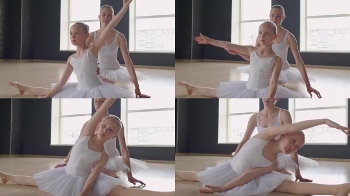 芭蕾舞老师在训练中帮助女孩把身体拉到腿上