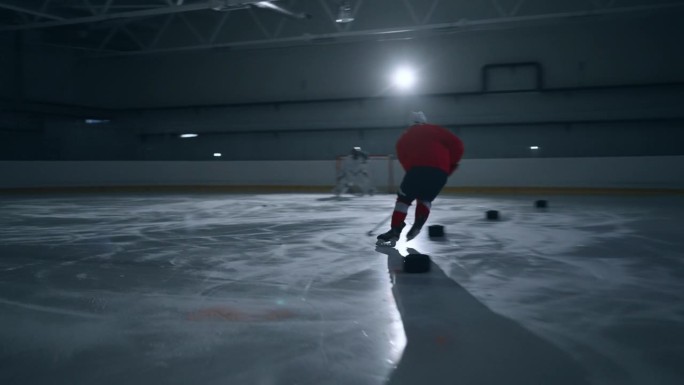一名身穿红色球衣的冰球运动员展示了专业技术，在冰上快速移动并得分的动态画面