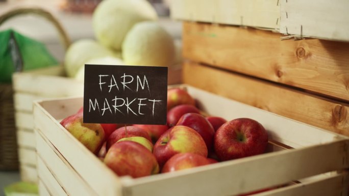 有农贸市场标志的精选红苹果与新鲜的有机水果和蔬菜。户外市场出售来自当地农田的环保生物产品