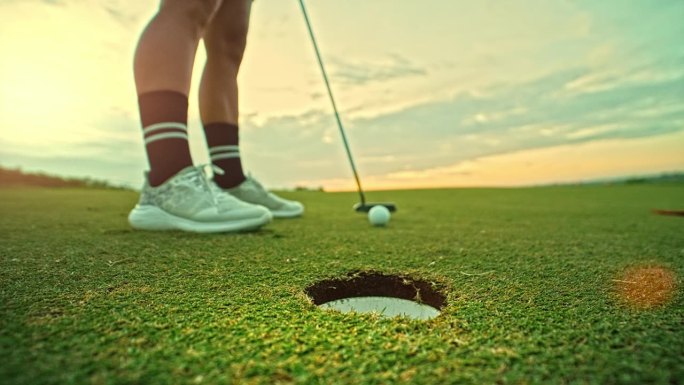 运动女子在高尔夫球场上玩游戏和击球到洞的俱乐部。女运动员用推杆和高尔夫球的快乐训练。积极职业人士的现