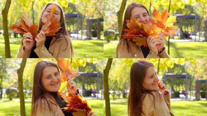 在秋天的公园里，快乐的微笑的女人捧着红枫树跳舞，笑着。美在自然，落在城市，幸福女人。