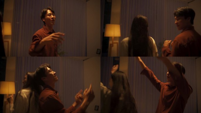 幸福的韩国伴侣在一起度过一个晚上，在家里随着轻松的音乐跳舞。快乐的亚洲夫妇手牵着手，在他们的客厅里玩