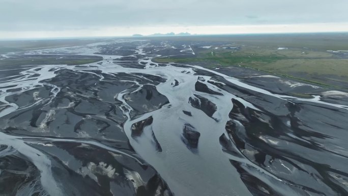 高角度平移拍摄，显示一条辫状河流流经冰岛的火山景观