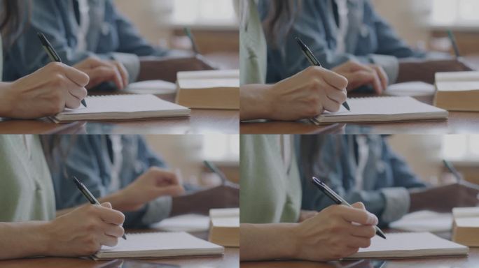 大学教室里，男女双手在笔记本上写字，触摸书桌上的书