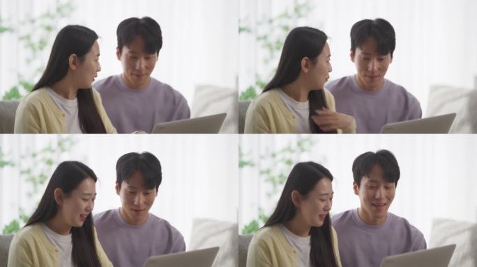 一对幸福的韩国夫妇在家里度过美好时光，在舒适的公寓里营造和谐的氛围，在笔记本电脑上观看韩剧
