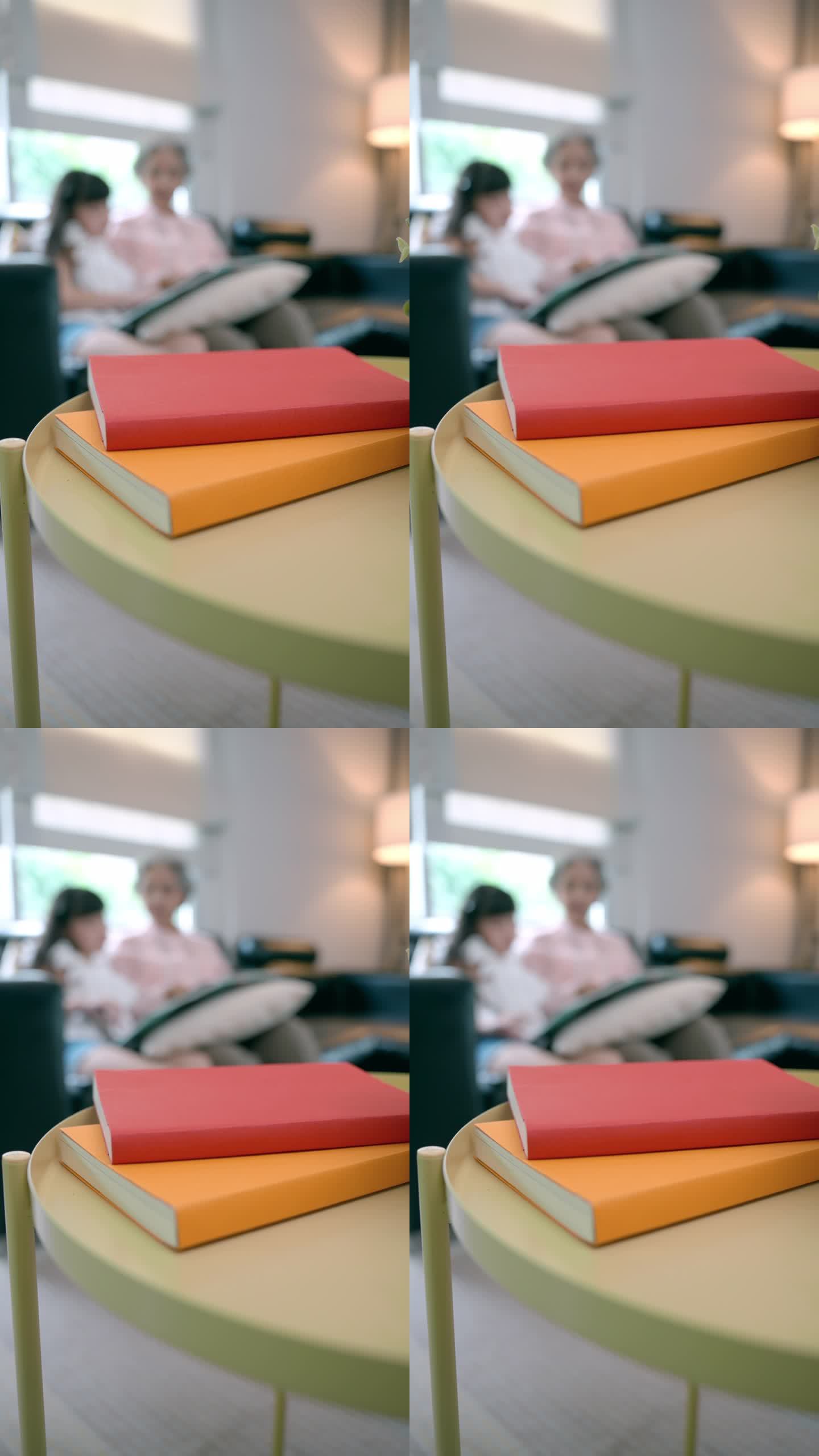 客厅的木桌上放着两本红色和橙色封面的书，快乐的老奶奶用相册给小侄女展示过去的回忆。