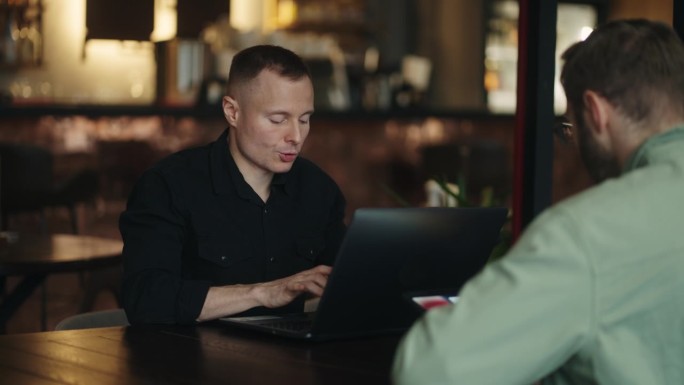 自由职业者在咖啡馆工作，男性IT和网页设计专业人士坐在桌子上用笔记本电脑