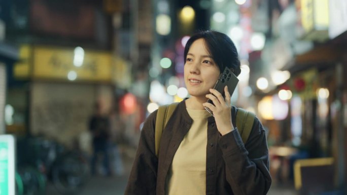 在日本旅游期间，一位迷人的亚洲女性与家人用智能手机聊天。