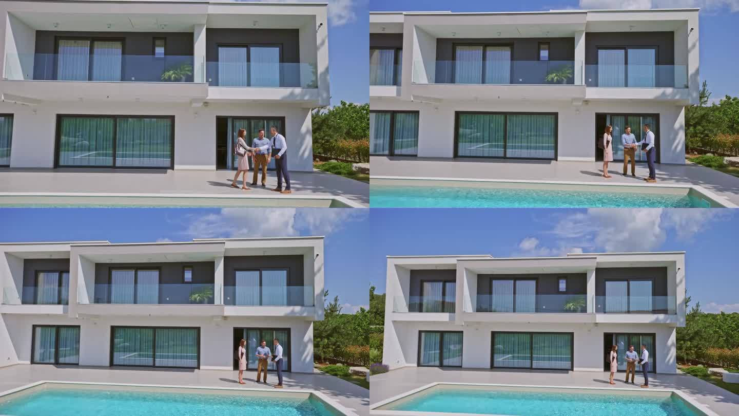 CS男房地产经纪人在带游泳池的豪宅后院与一对已婚夫妇握手