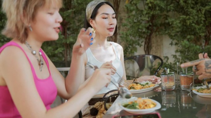 亚洲旅行团在曼谷的度假之旅中，在当地餐馆品尝泰国街头小吃，享受乐趣。