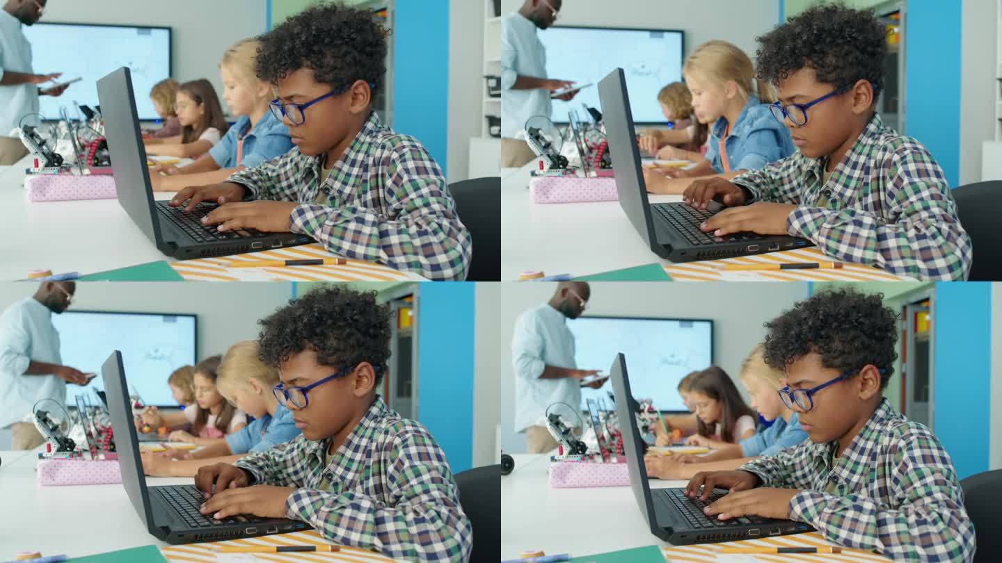 黑人男孩在儿童科技俱乐部为电动机器人编写计算机程序