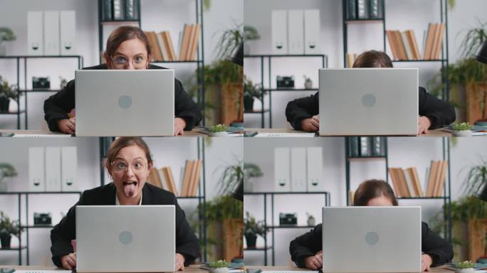 办公室女商人躲在笔记本电脑后面，做着滑稽的傻脸，胡闹，不尊重