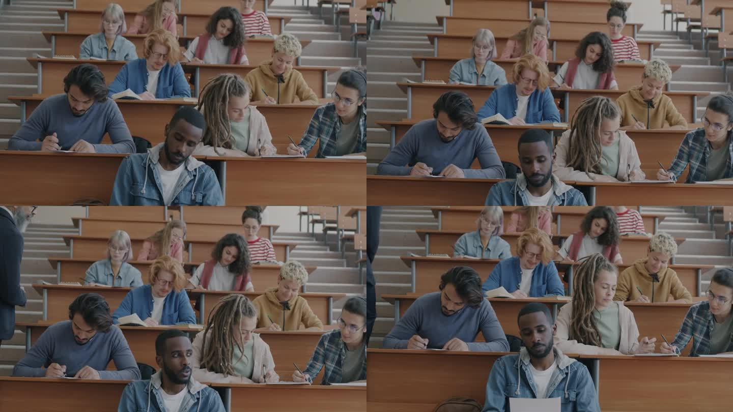 多种族的学生，女生和男生，考试的重点是教育，坐在礼堂的课桌前