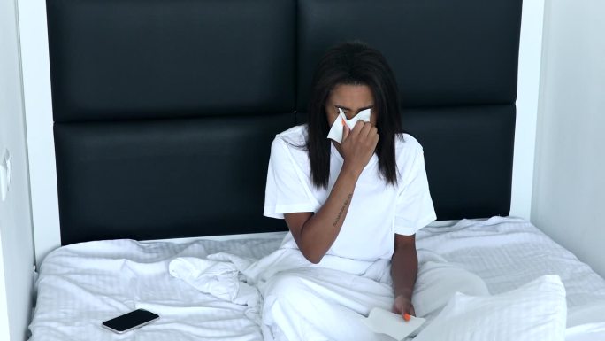 生病的黑人妇女流鼻涕，鼻塞，喉咙痛。