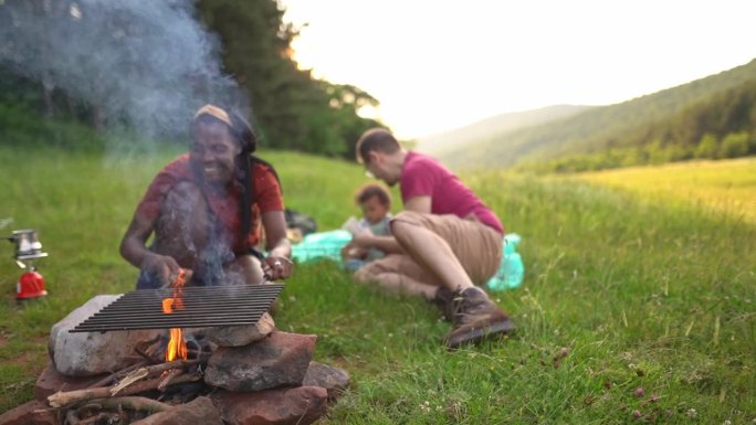 一个多种族家庭和一个男婴在草地上生火烧烤