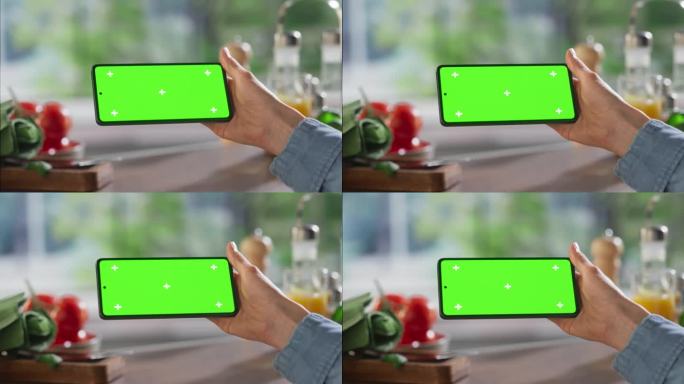 匿名妇女使用智能手机，在厨房桌子上模拟绿屏Chromakey显示屏，上面有餐具和食物配料。女性观看横