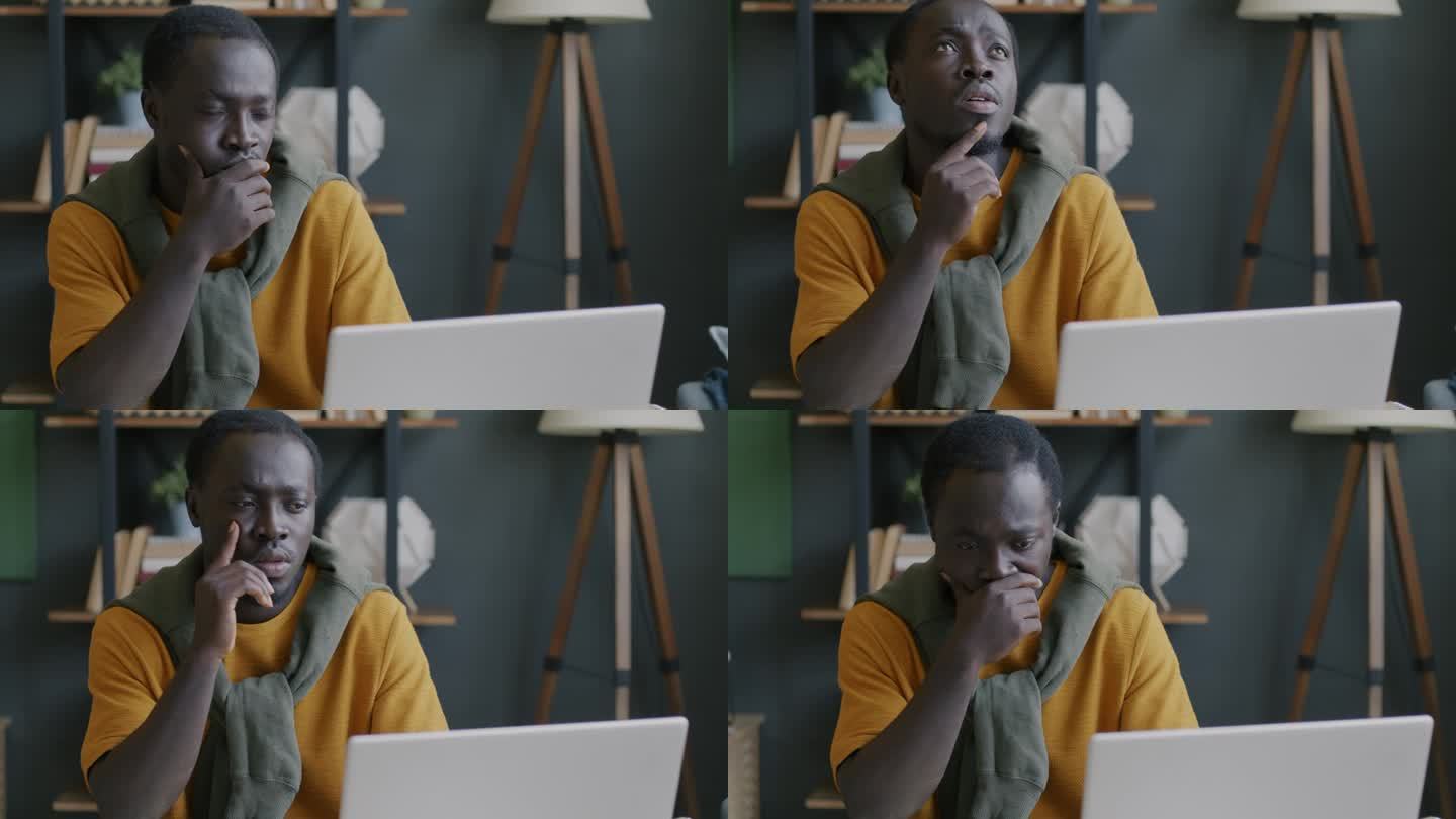 一个沉思的非裔美国人，他在办公室里用笔记本电脑工作，思考着困难的挑战