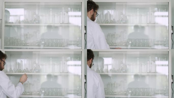 一名男性实验室技术员在干净的实验室打开玻璃柜的后视图