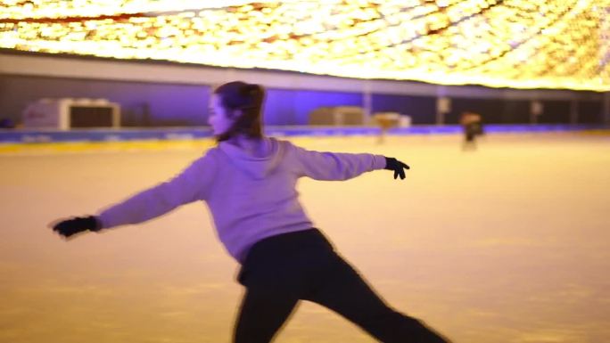 跟踪拍摄自信优雅的女运动员骑溜冰鞋在溜冰场旋转。现场摄像机跟随苗条迷人的白人妇女在夜间城市户外训练。