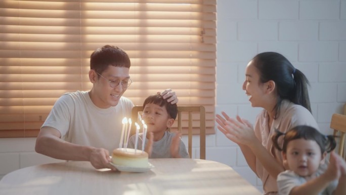 快乐的亚洲家庭在家里与儿子和女儿庆祝生日。