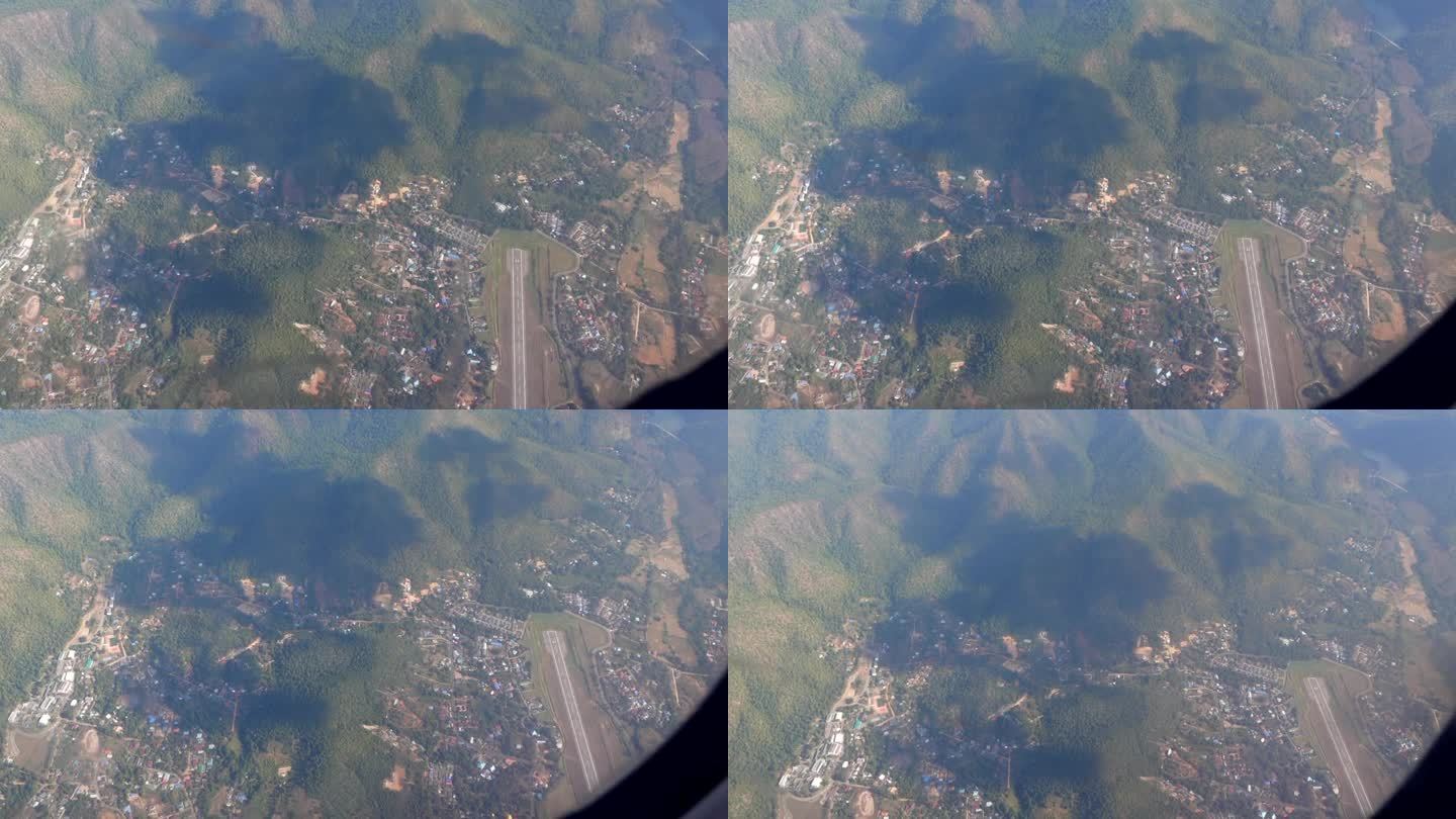 俯览泰国小机场跑道和当地小镇山地上空的飞机窗景