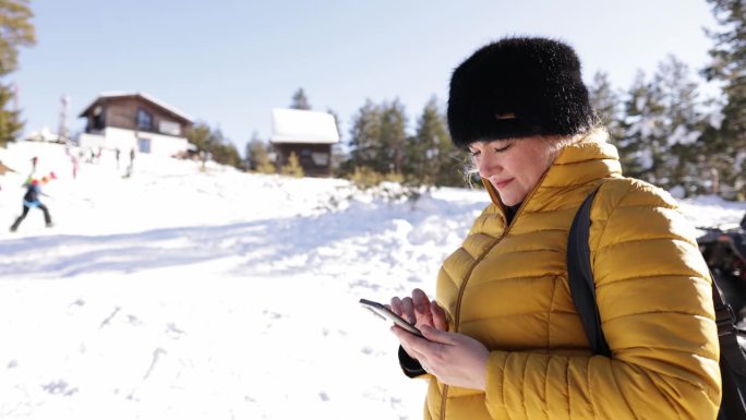 一名高加索妇女在她的寒假期间在山上使用手机